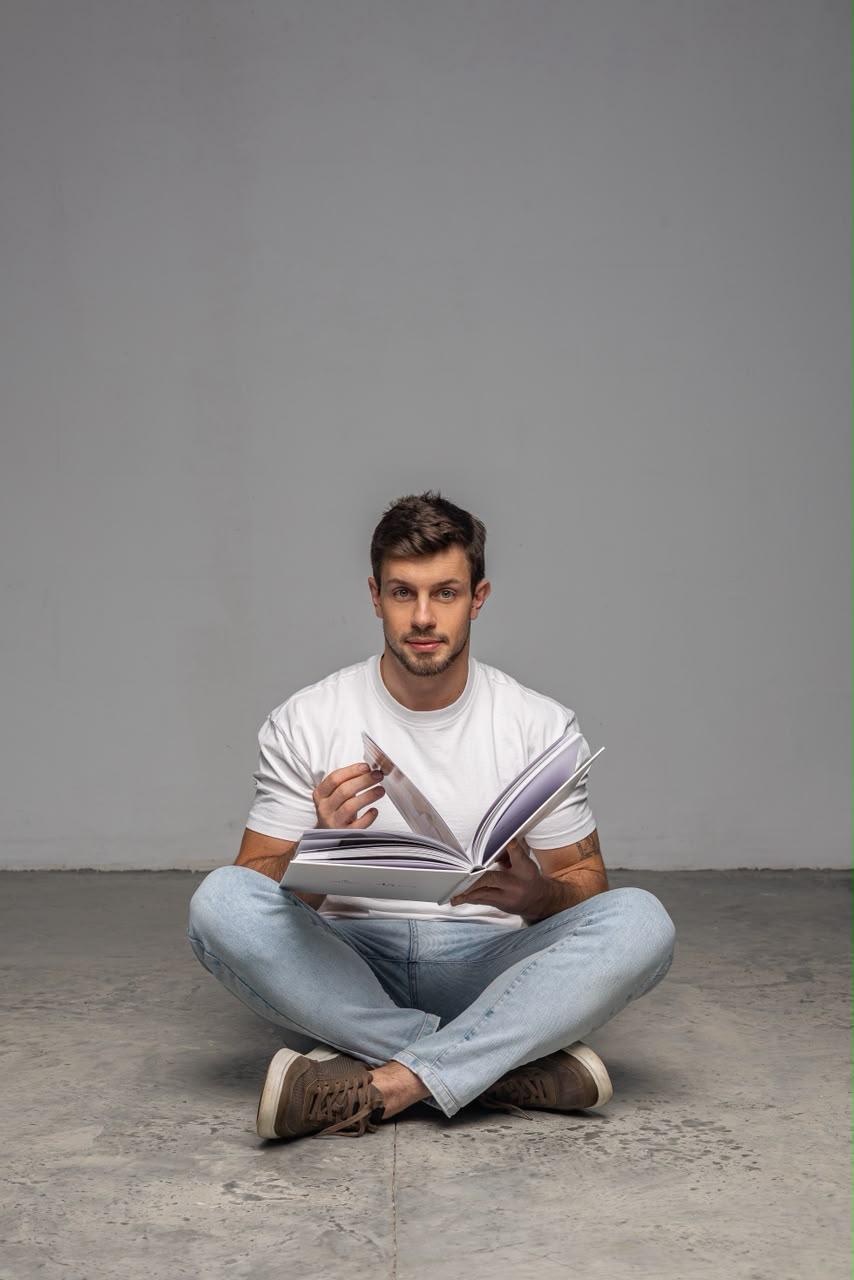 Davi Butzke sentado no chão, estudando com um livro aberto